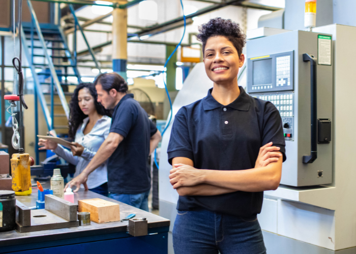 women smiling with manufacturing plant behind