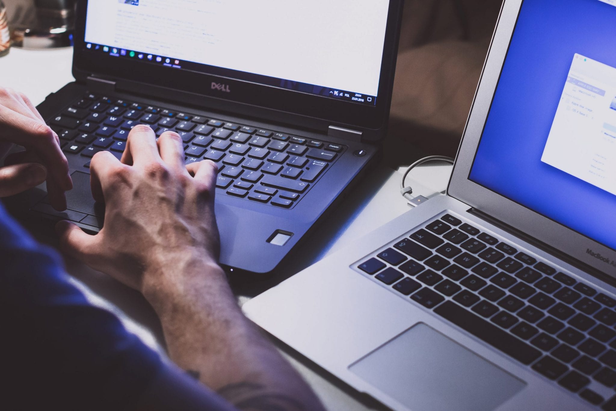 person working with 2 laptops