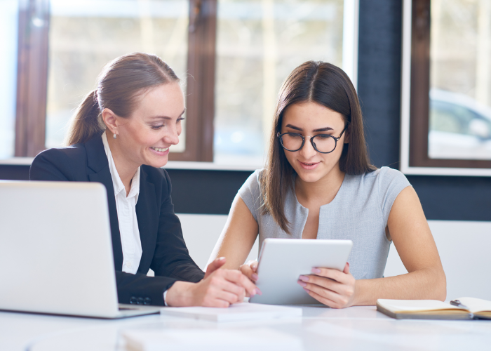 Two women looking at computer and tablet screens